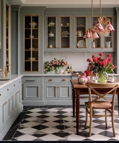 a kitchen with checkered flooring and cabinets in the center, flowers on the dining room table