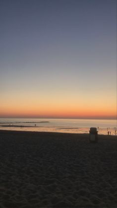 the sun is setting at the beach and people are out in the water