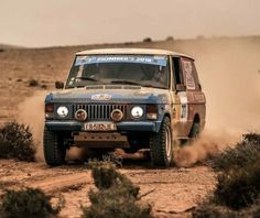 an old jeep driving through the desert with dust coming off it's front tires