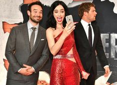 two men and a woman standing next to each other in front of a red carpet