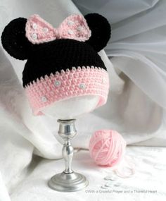 a crocheted minnie mouse hat sitting on top of a table next to a ball of yarn