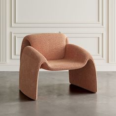 an orange chair sitting on top of a cement floor next to a white paneled wall