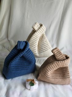 three crocheted purses sitting on top of a white bed next to each other