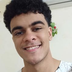 a close up of a person wearing a flower on his head and smiling at the camera