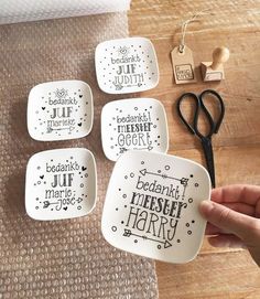 four small dishes with words on them are being held up by someone's hand