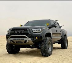 a large gray truck parked on top of a sandy beach