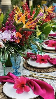 the table is set with place settings and colorful flowers in vases on each plate