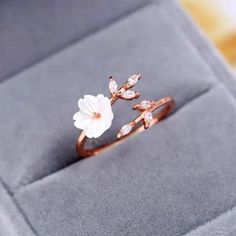 a white flower is sitting on top of a ring in a box with its lid open