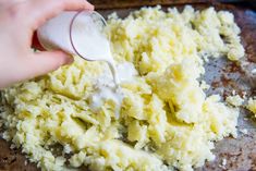 someone is adding mayonnaise to mashed potatoes on a baking sheet with other ingredients