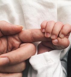 a person holding a baby's hand in the palm of their left hand,