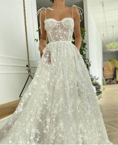 a woman in a white wedding dress standing on the floor with her hands behind her back