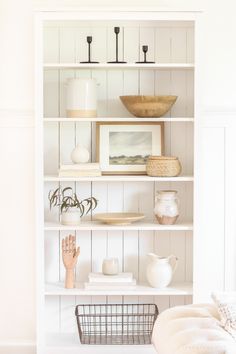 a white bookcase filled with vases and other items on top of it's shelves