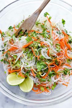 a glass bowl filled with shredded carrots, cabbage and cilantro sprouts