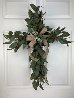 a cross made out of burlocks and greenery hangs on the front door