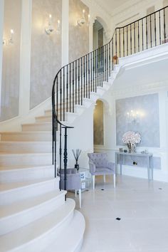 a white staircase in a home with chandelier and chairs on the side walk