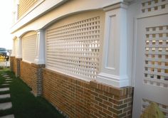 a brick wall with white trim around it and green grass in front of the building