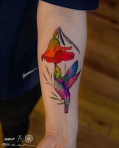 a colorful hummingbird tattoo on the left inner arm