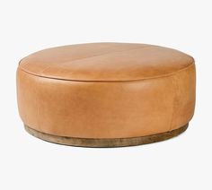 a tan leather ottoman sitting on top of a white floor