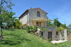 an old stone house with green grass and trees