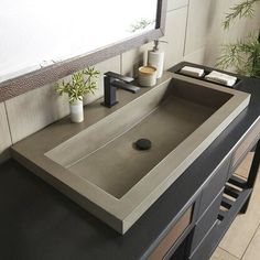 a bathroom sink sitting under a mirror next to a counter top with a plant on it