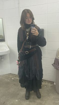 a woman is taking a selfie with her cell phone in the bathroom while wearing steampunk clothing