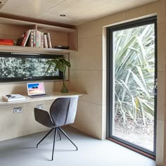 a desk with a laptop on it in front of a window and bookshelf