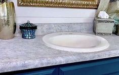 a white sink sitting on top of a bathroom counter next to a blue cabinet and mirror