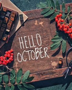 the word hello october written on a wooden board surrounded by berries and other items such as scissors