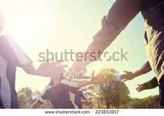 group of people holding hands in the middle of a circle with sunlight shining on them