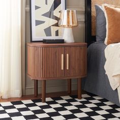 a bed with a black and white checkered floor next to a wooden nightstand on top of it