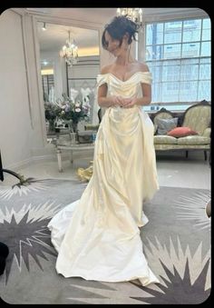 a woman in a wedding dress looking down at her phone while standing on the floor