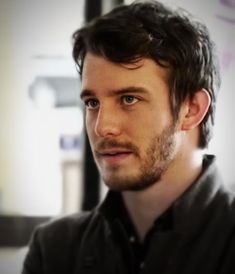 a close up of a person wearing a black shirt and looking at the camera with a serious look on his face