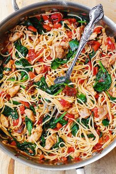 a skillet filled with pasta, meat and veggies on a wooden table