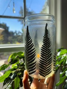 a person holding up a glass with some plants in it