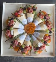 an arrangement of fruits and flowers arranged in a circle on top of a white box