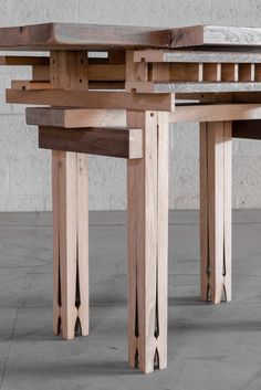 three wooden tables sitting next to each other on top of cement floored area with concrete walls in the background