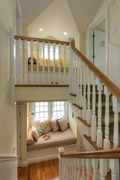 there is a couch under the stairs in this house with wood floors and white railings