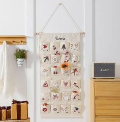 a wall hanging on the side of a white wall next to a wooden dresser and chair