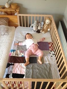 a baby laying in a crib next to stuffed animals