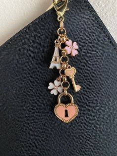 a close up of a key chain with charms on it's end and a heart shaped lock hanging from the front