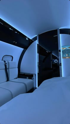 the interior of an airplane that is lit up with blue lights and white bedding