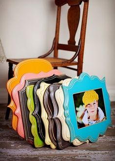 a group of frames sitting next to each other on top of a wooden floor with a chair in the background