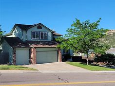 a two story house on the corner of a street with trees in front of it