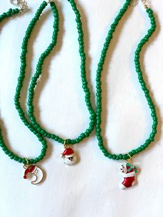 three green beaded necklaces with santa hats and bells hanging from each strander