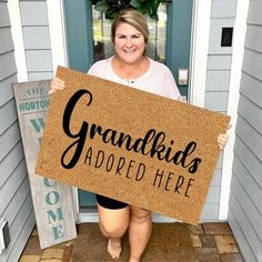 a woman holding a sign that says grandkids adopted here