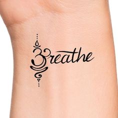 a woman's wrist with the word breathe written in cursive writing on it