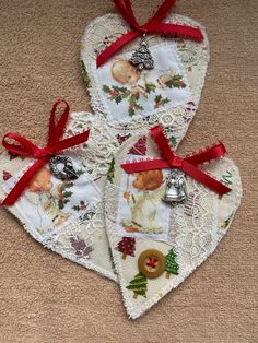 three heart shaped christmas ornaments with red bows and bells hanging from them on the floor