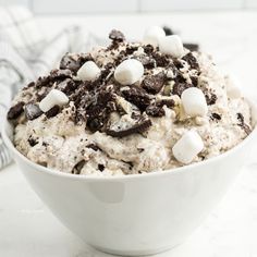 a bowl filled with cookies and marshmallows on top of a white counter