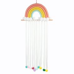 a rainbow mobile hanging from a wooden stick with pom poms on the end