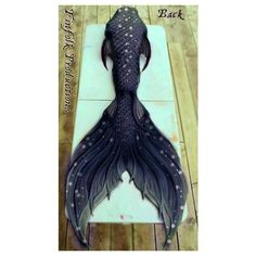 a paper cut out of a mermaid tail on a wooden floor with words underneath it